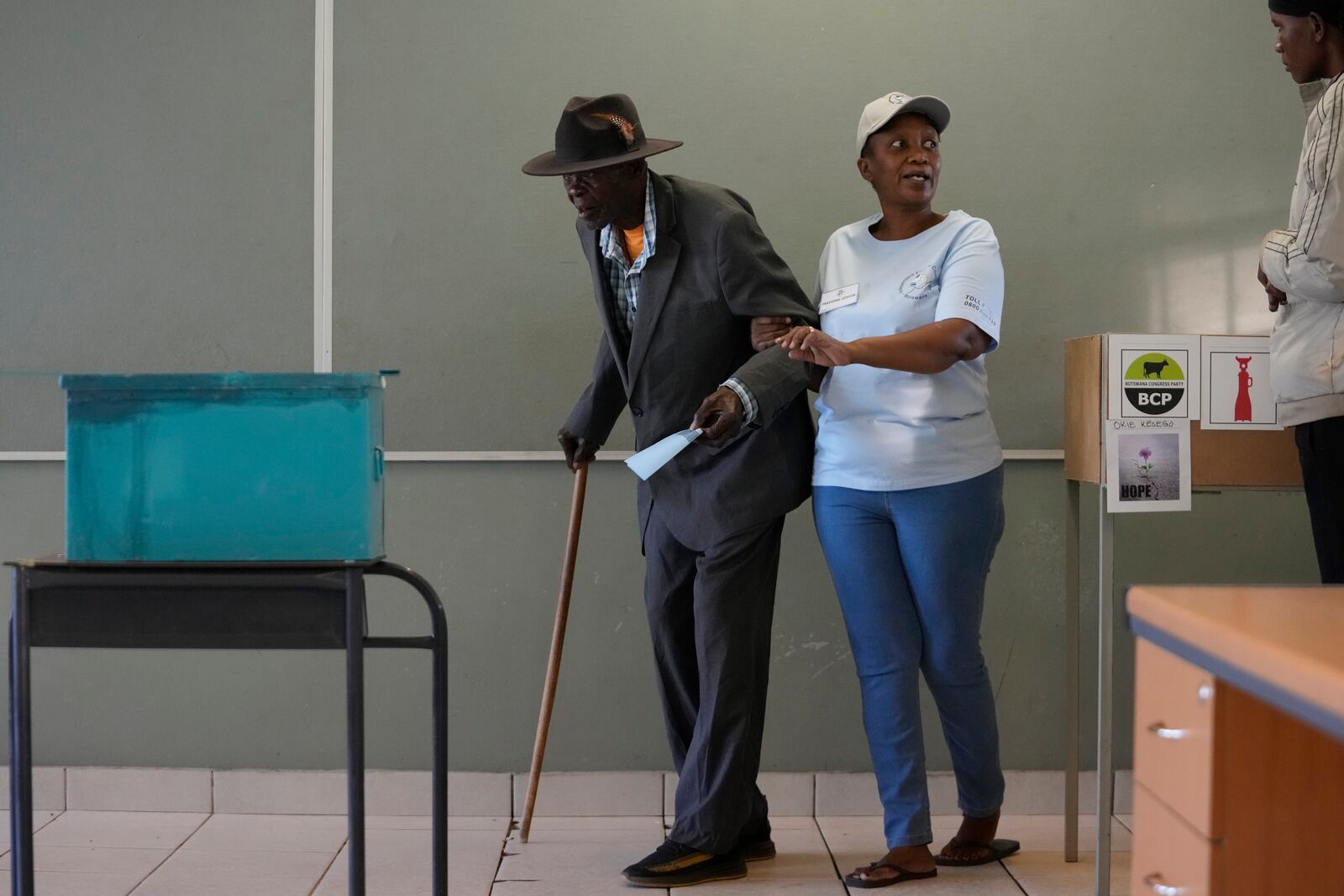 A man assisted by an electoral worker, walks towards the ballot box to cast his vote during the elections in Gaborone, Botswana, Wednesday, Oct. 30, 2024. (AP Photo/Themba Hadebe)