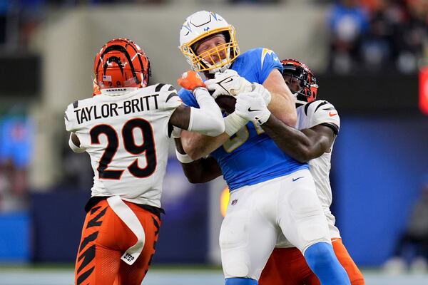 Los Angeles Chargers tight end Will Dissly (81) is tackled by Cincinnati Bengals cornerback Cam Taylor-Britt (29) and linebacker Germaine Pratt during the first half of an NFL football game Sunday, Nov. 17, 2024, in Inglewood, Calif. (AP Photo/Gregory Bull)