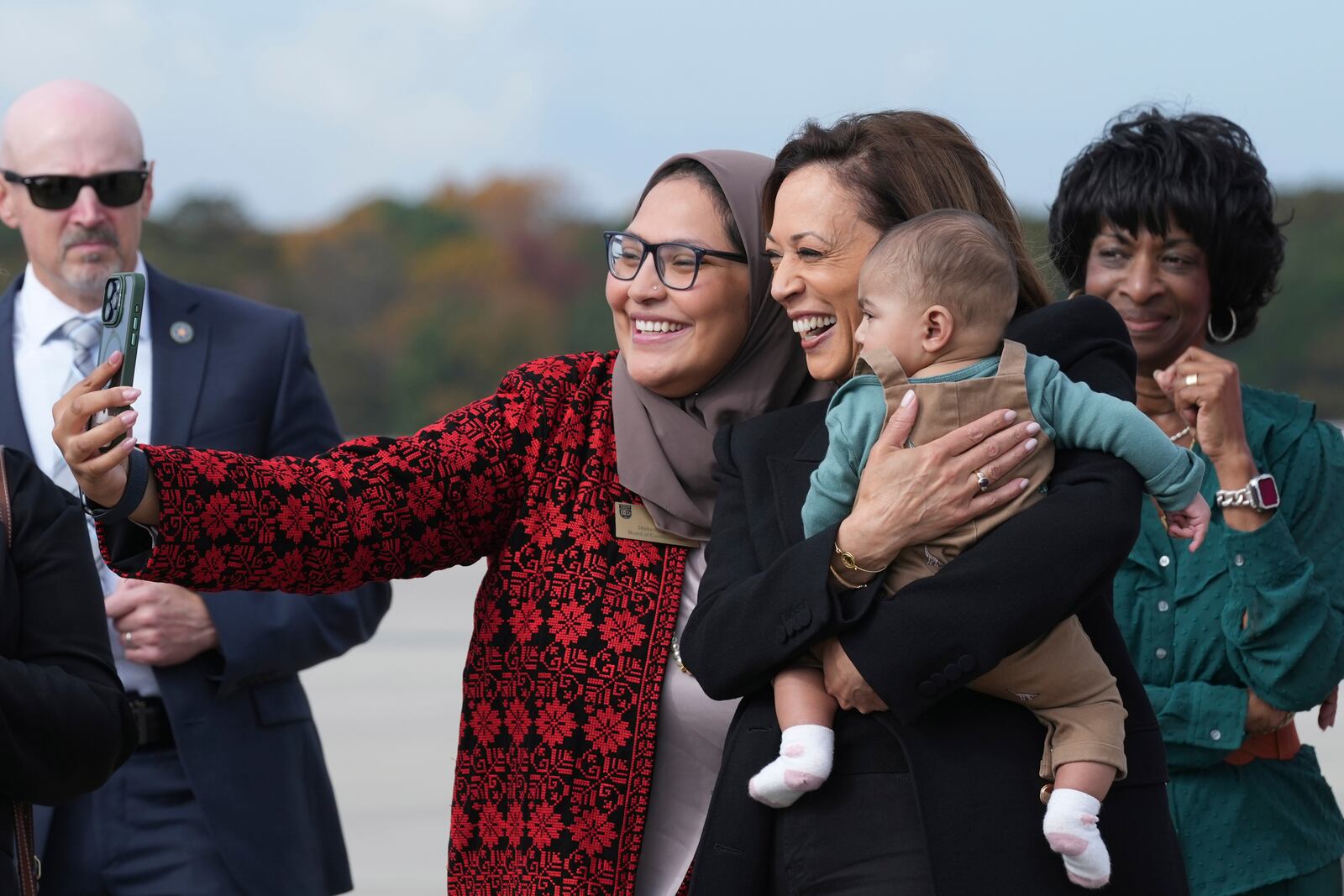 Democratic presidential nominee Vice President Kamala Harris poses for a photo with Chairwoman Nida Allam, Durham County Board of Commissioners, center, as Rep. Valerie Foushee, D-N.C., right, looks on, as she arrives at Raleigh–Durham International Airport in Morrisville, N.C., Wednesday, Oct. 29, 2024. (AP Photo/Susan Walsh)