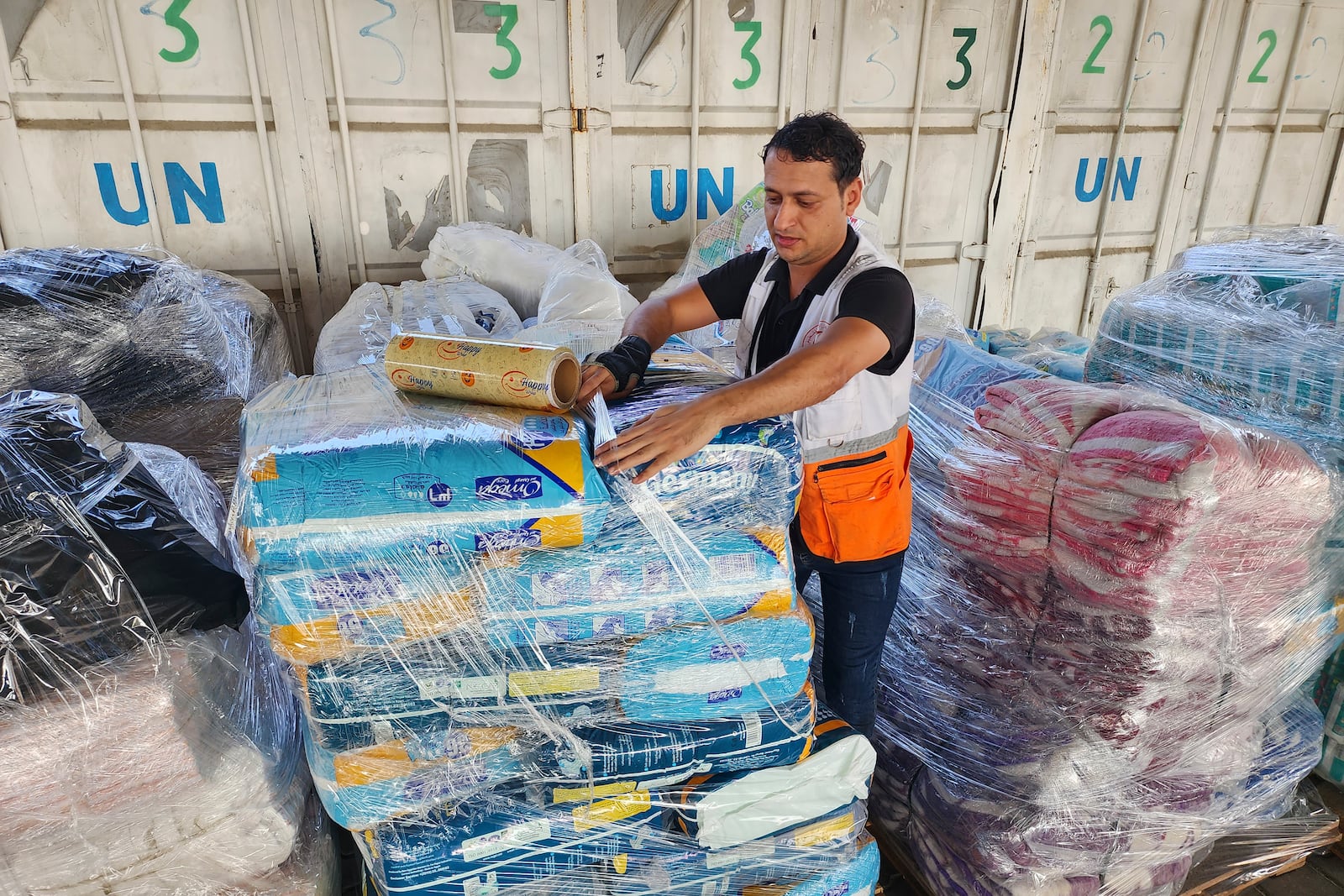 FILE - United Nations and Red Crescent workers prepare the aid for distribution to Palestinians at UNRWA warehouse in Deir Al-Balah, Gaza Strip, on Monday, Oct. 23, 2023. (AP Photo/Hassan Eslaiah, File)