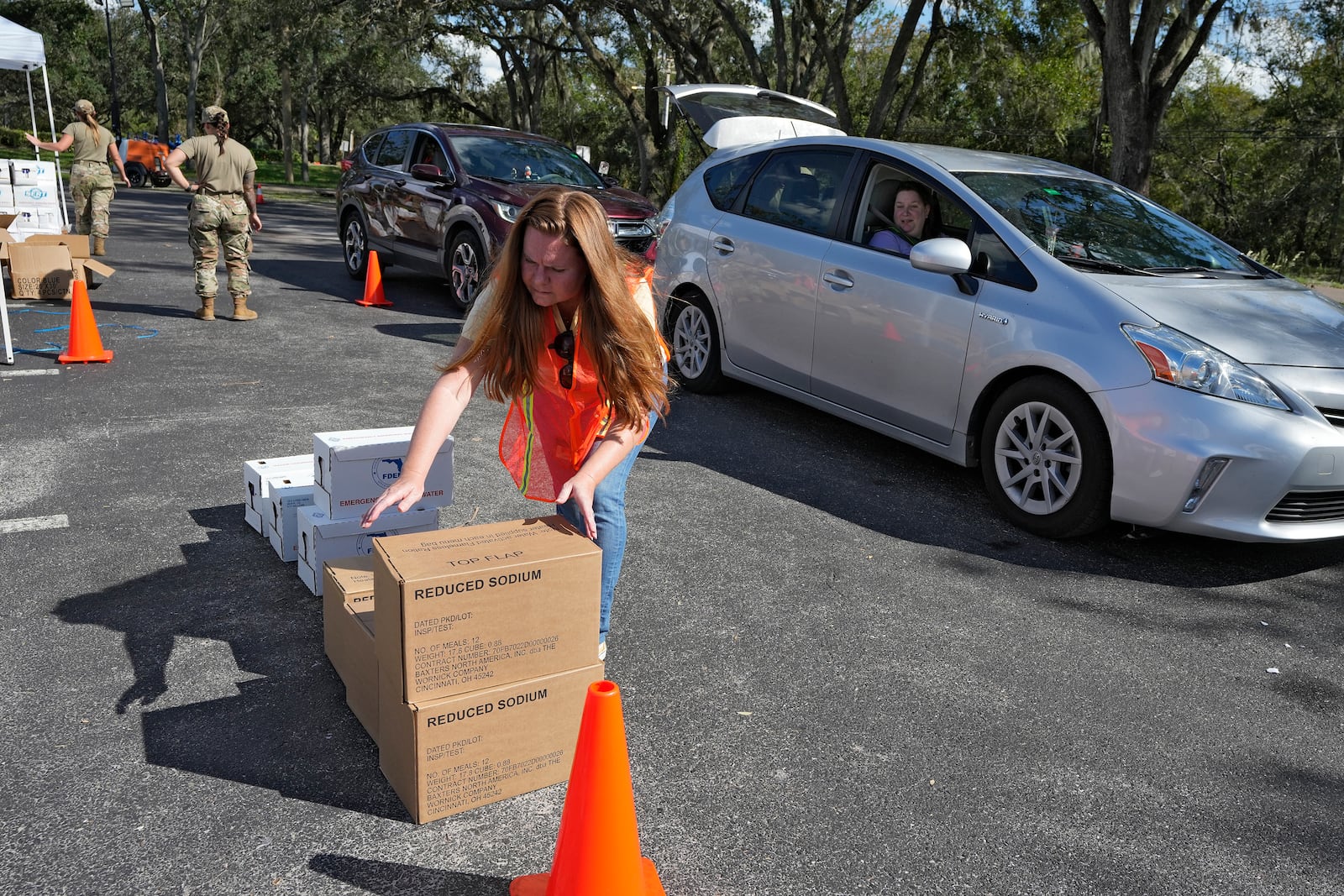 Hillsborough County employee Priscille Traugh helps load supplies into the cars of residents displaced by Hurricane Milton, Sunday, Oct. 13, 2024, at the Hillsborough Community College campus in Brandon, Fla. (AP Photo/Chris O'Meara)