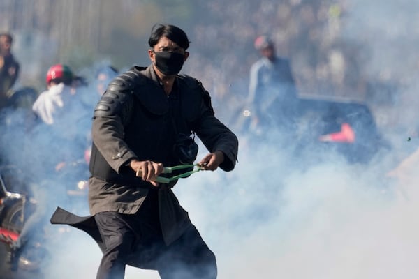 A supporters of imprisoned former premier Imran Khan's Pakistan Tehreek-e-Insaf party, aims to throw stones with slingshot following police fire tear gas shell to disperse them during clashes, in Islamabad, Pakistan, Tuesday, Nov. 26, 2024. (AP Photo/Anjum Naveed)