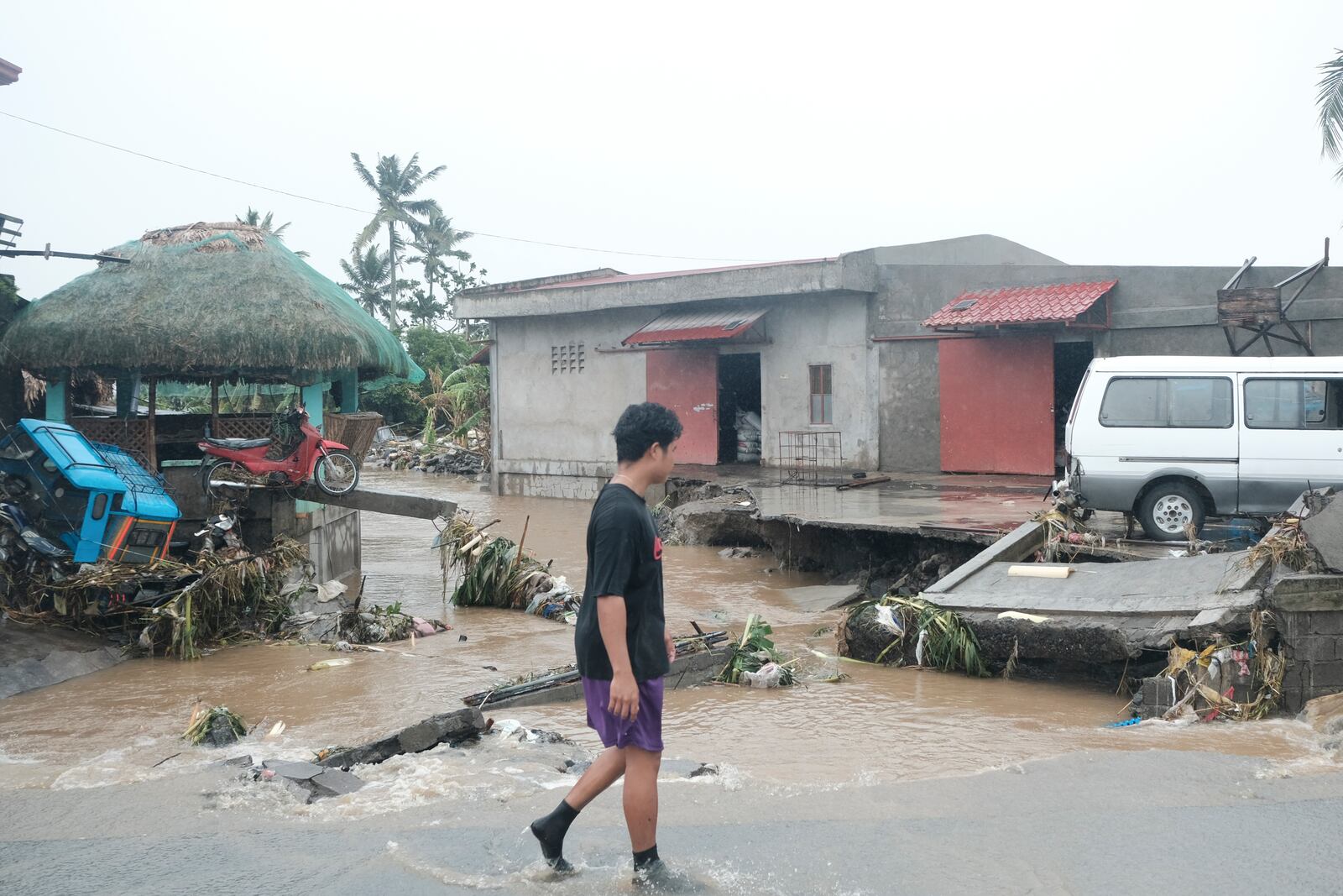 A man walks past damages caused by flash floods on Thursday Oct. 24, 2024 after Tropical Storm Trami, locally named Kristine, dumped heavy rains at Libon town, Albay province, Philippines. (AP Photo/John Michael Magdasoc)