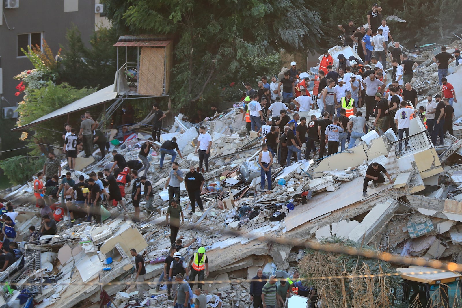 People and rescue workers search for victims after an Israeli airstrike hit two adjacent buildings, in Ain el-Delb neighbourhood east of the southern port city of Sidon, Lebanon, Sunday, Sept. 29, 2024. (AP Photo/Mohammed Zaatari)