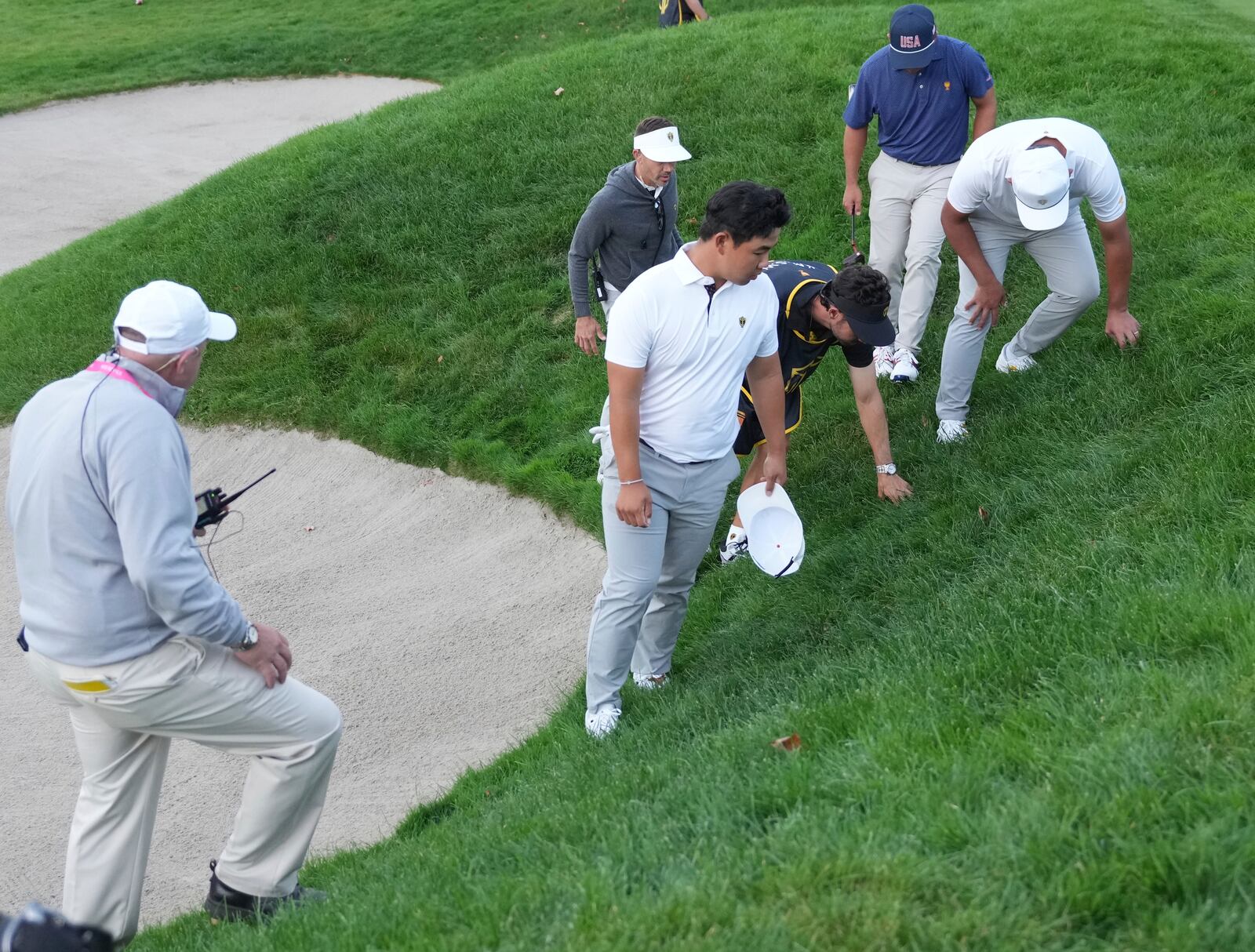 International team member Si Woo Kim, center front, of South Korea, looks for his ball on the16th hole during a fourth-round foursomes match at the Presidents Cup golf tournament at Royal Montreal Golf Club in Montreal, Saturday, Sept. 28, 2024. (NathanDenette/The Canadian Press via AP)