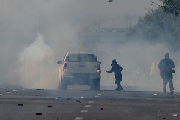 Supporters of imprisoned former Premier Imran Khan's Pakistan Tehreek-e-Insaf party run for cover as police fire tear gas shells to disperse them during clashes in Islamabad, Pakistan, Tuesday, Nov. 26, 2024. (AP Photo/Anjum Naveed)