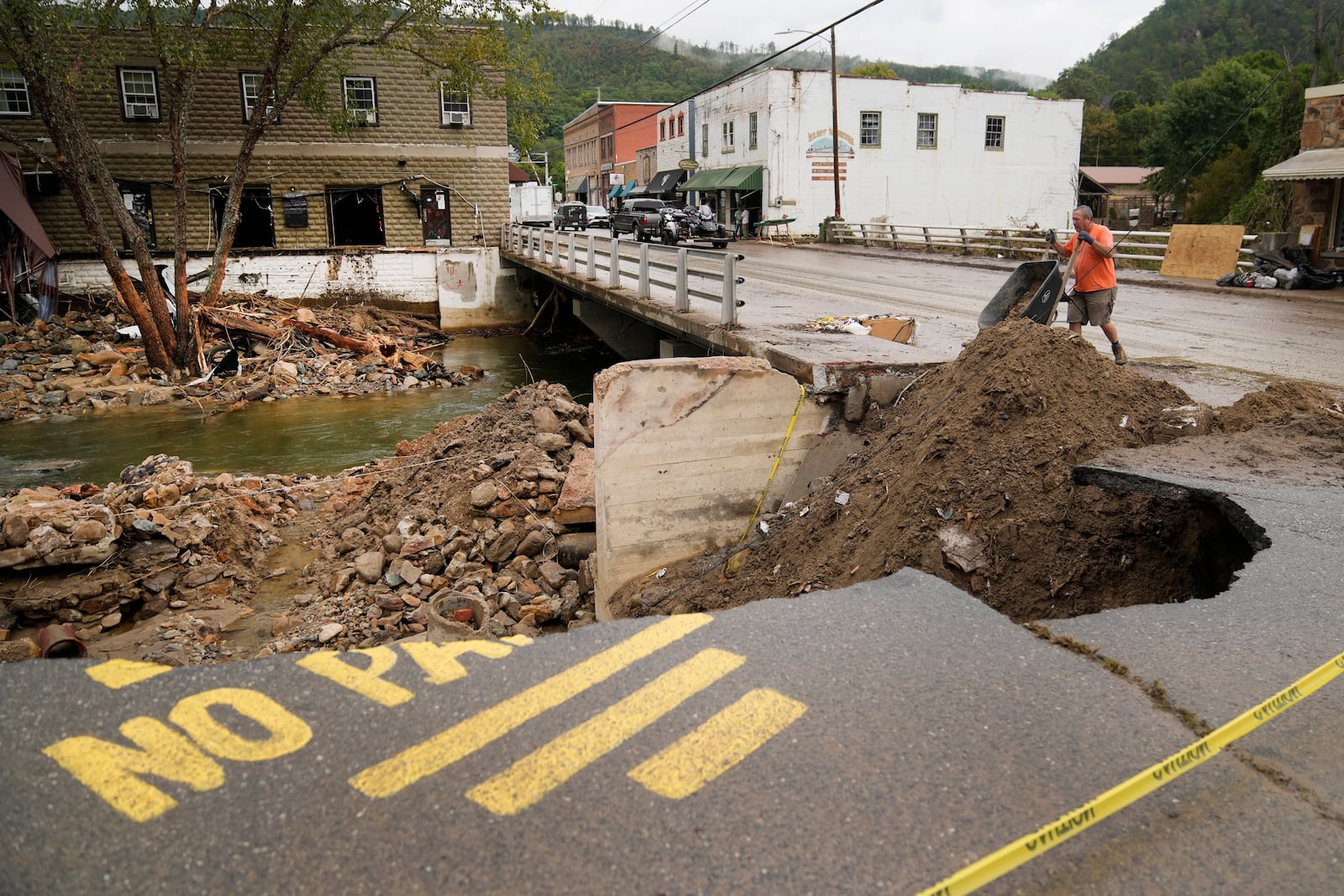 FILE - Len Frisbee dumps a wheelbarrow of dirt as he helps with clean up in the aftermath of Hurricane Helene, Oct. 1, 2024, in Hot Springs, N.C. (AP Photo/Jeff Roberson, File)