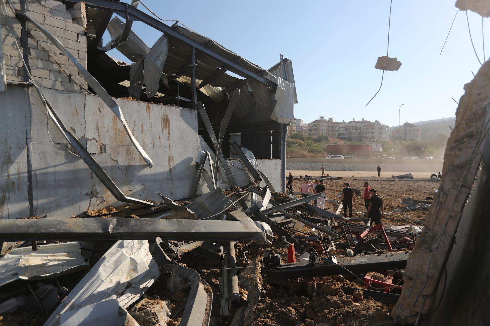 People gather at the site of an Israeli airstrike that hit a hangar in the southern town of Jiyeh, Lebanon, Wednesday, Sept. 25, 2024. (AP Photo/Mohammed Zaatari)