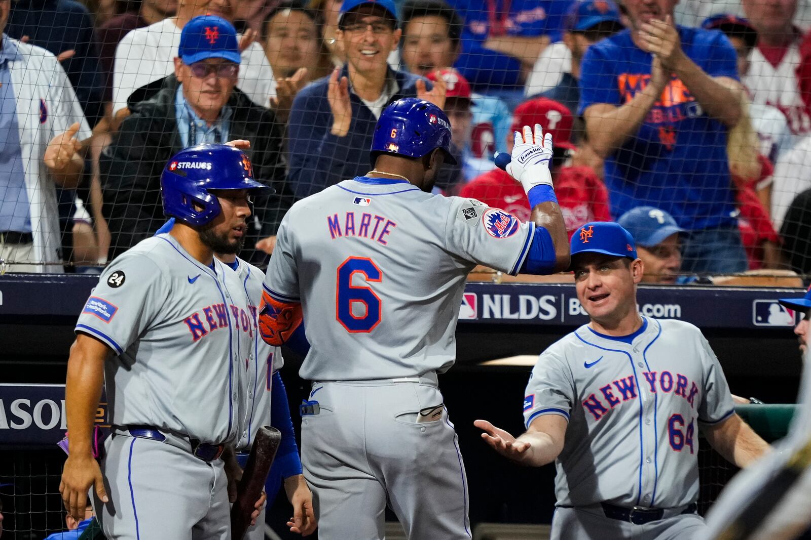 New York Mets' Starling Marte (6) celebrates after hitting an RBI sacrifice fly with New York Mets manager Carlos Mendoza (64) during the eighth inning of Game 1 of a baseball NL Division Series, Saturday, Oct. 5, 2024, in Philadelphia. (AP Photo/Matt Slocum)