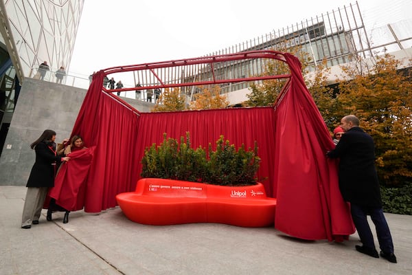 People participate in the unveiling of a red bench on the occasion of the International Day for the Elimination of Violence against Women, in Milan, Italy, Monday, Nov. 25, 2024. (AP Photo/Luca Bruno)