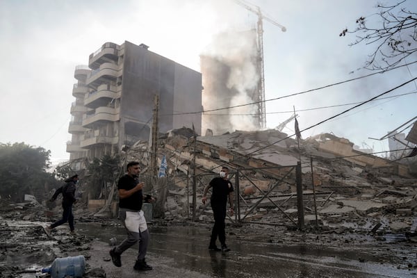 Residents run as smoke rises from a building that collapsed after it was hit by an Israeli airstrike in Chiyah, south of Beirut, Lebanon, Sunday, Nov. 17, 2024. (AP Photo/Bilal Hussein)