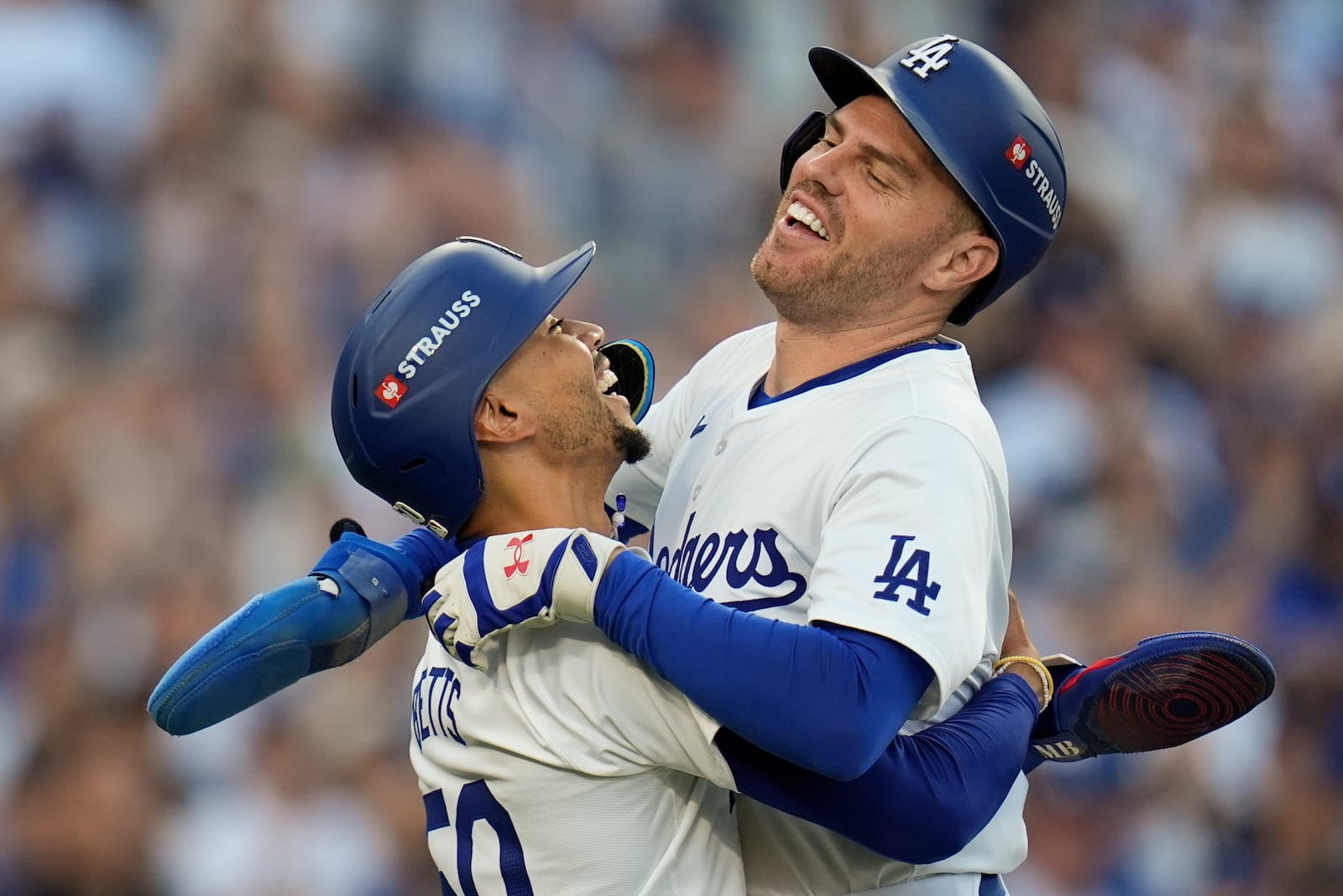 Los Angeles Dodgers' Freddie Freeman, right, and Mookie Betts celebrate after they scored on a single by Max Muncy during the first inning in Game 1 of a baseball NL Championship Series against the New York Mets, Sunday, Oct. 13, 2024, in Los Angeles. (AP Photo/Gregory Bull)