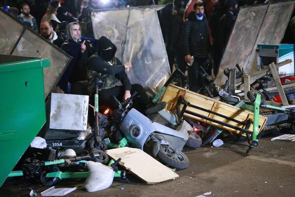 Demonstrators sit at a barricade during a rally outside the parliament's building to protest the government's decision to suspend negotiations on joining the European Union for four years in Tbilisi, Georgia, early Sunday, Dec. 1, 2024. (AP Photo/Zurab Tsertsvadze)