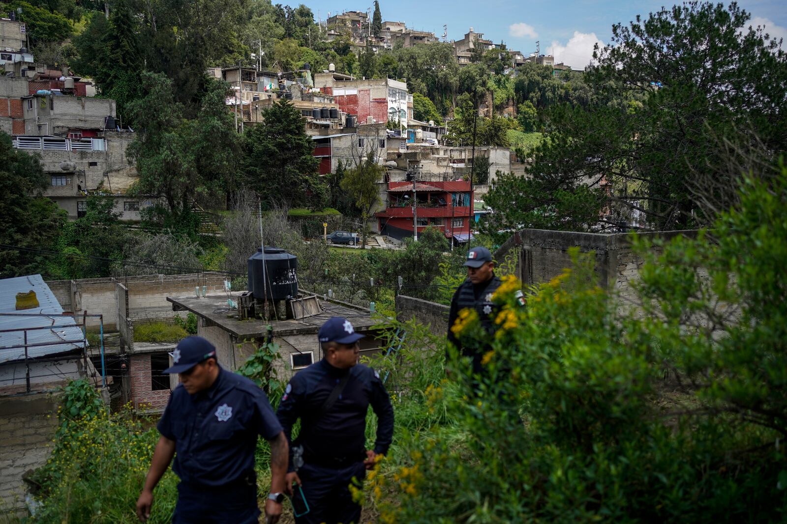 Municipal police officers guard the area where various people died after a rain-induced landslide, in Naucalpan, Mexico, Tuesday, Sept. 17, 2024. (AP Photo/Felix Marquez)