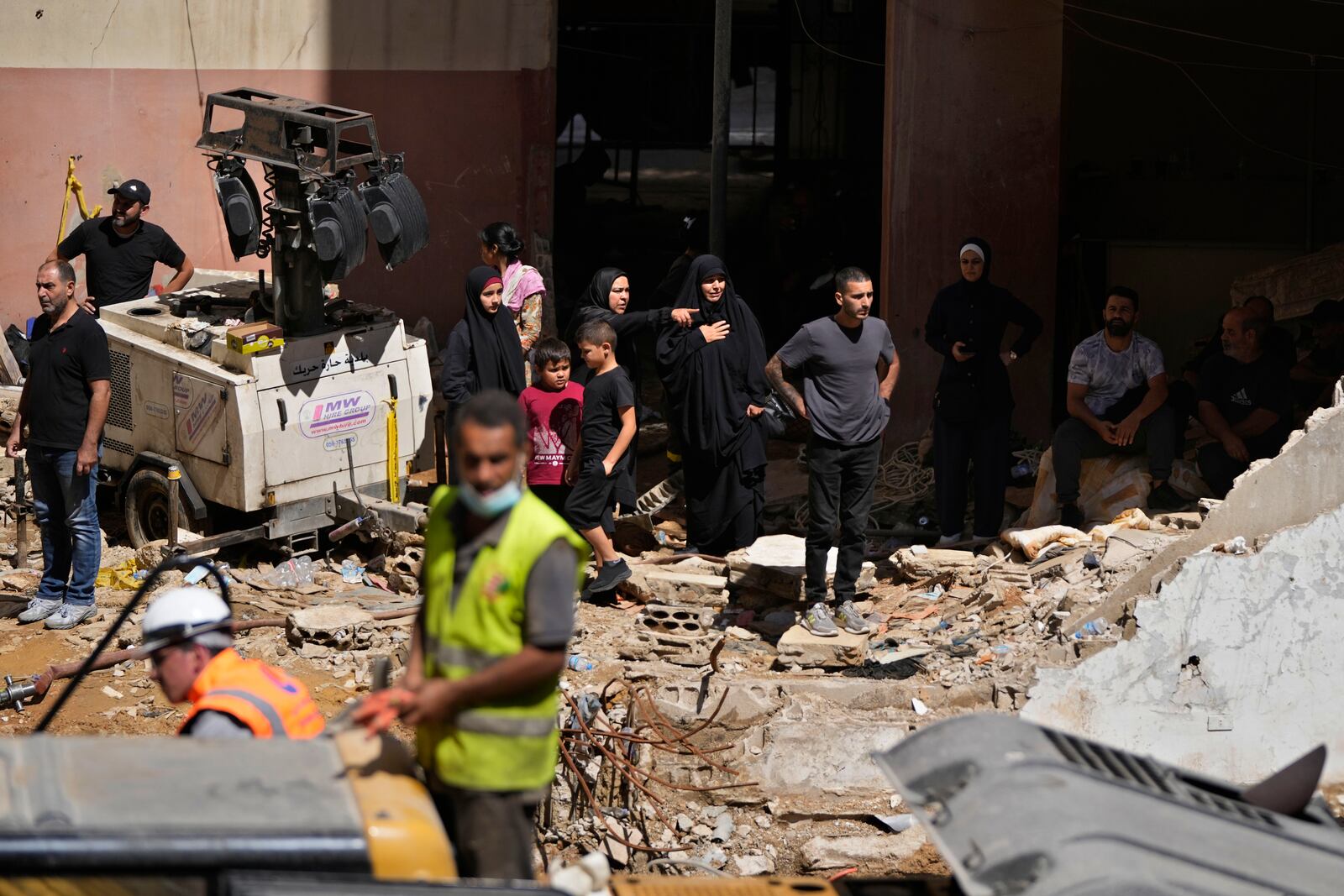 Residents react as rescuers sift through the rubble as they search for people still missing at the site of Friday's Israeli strike in Beirut's southern suburbs, Monday, Sept. 23, 2024. (AP Photo/Hassan Ammar)