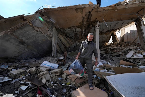 Ali Haidous carries a plastic bag with the remains of her family clothes, as he walks on the rubble of his destroyed house after he returned with his family to Hanouiyeh village, southern Lebanon, Thursday, Nov. 28, 2024 following a ceasefire between Israel and Hezbollah that went into effect on Wednesday.(AP Photo/Hussein Malla)