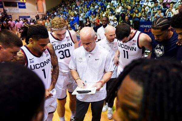 UConn head coach Dan Hurley huddles with his team, including guard Solo Ball (1), forward Liam McNeeley (30) and forward Alex Karaban (11) before facing Memphis in an NCAA college basketball game at the Maui Invitational Monday, Nov. 25, 2024, in Lahaina, Hawaii. (AP Photo/Lindsey Wasson)