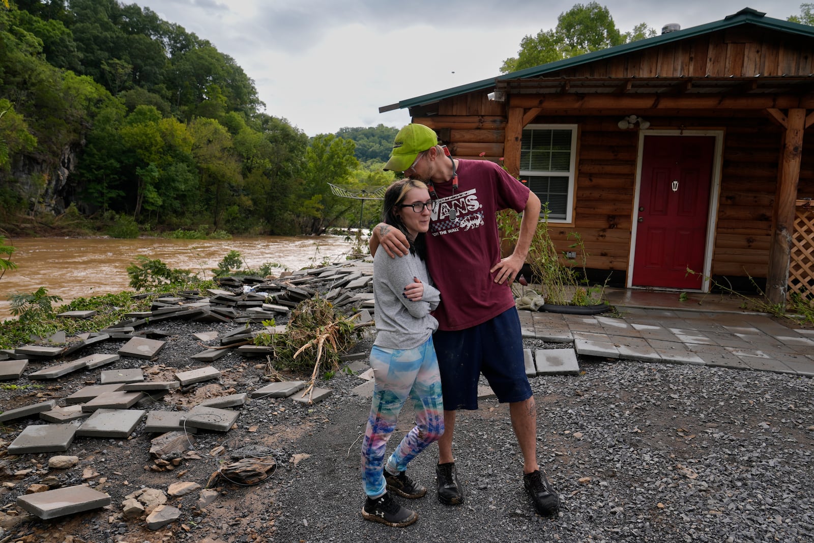 Jonah Wark, right, kisses his wife Sara Martin outside their flood damaged home on the Pigeon River, Saturday, Sept. 28, 2024, in Newport, Tenn. (AP Photo/George Walker IV)