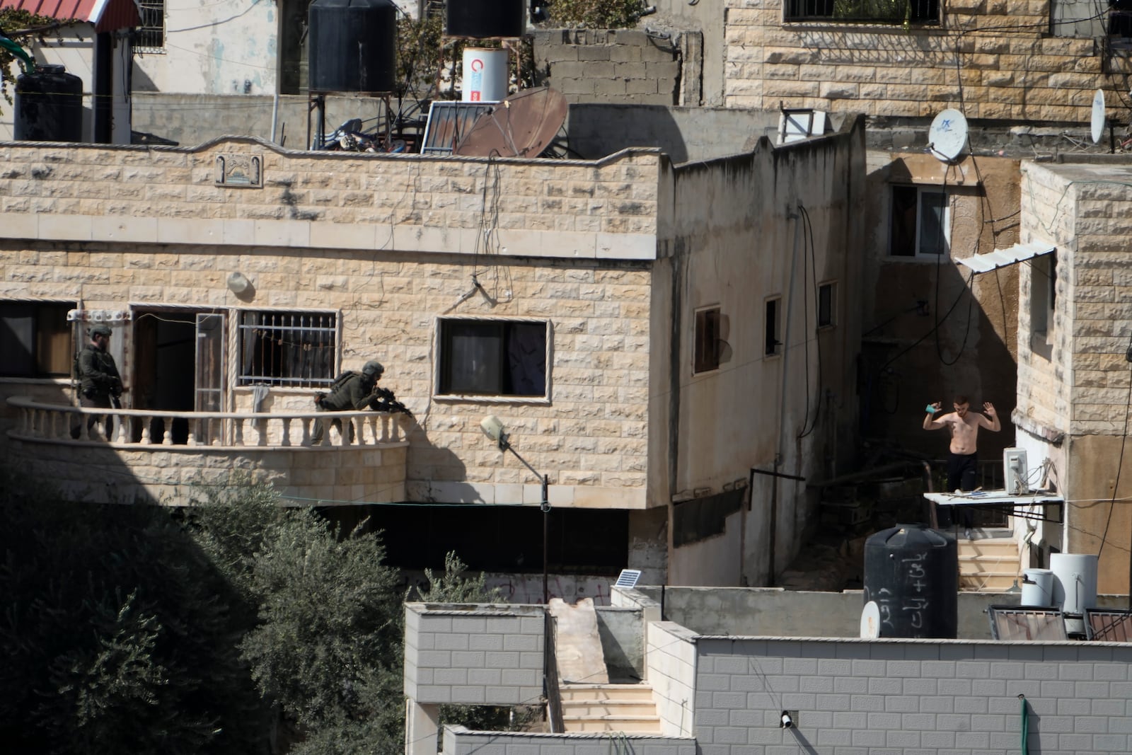 A man holds his hand while in the sight of two Israeli soldiers in the West Bank town of Qatabiya during a raid, Thursday, Sept.19, 2024. (AP Photo/Majdi Mohammed)