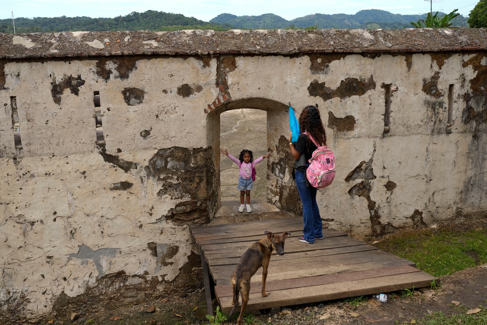 A woman takes a photo of her daughter at the San Jeronimo fort in Portobelo, Panama, Monday, Oct. 21, 2024, during a festival celebrating the iconic Black Christ statue that was found on the shore in 1658. (AP Photo/Matias Delacroix)