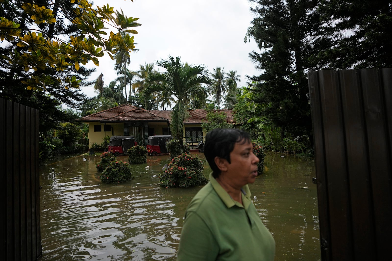 A woman stands outside her submerged house due to floods in Colombo, Sri Lanka, Sunday, Oct. 13, 2024. (AP Photo/Eranga Jayawardena)