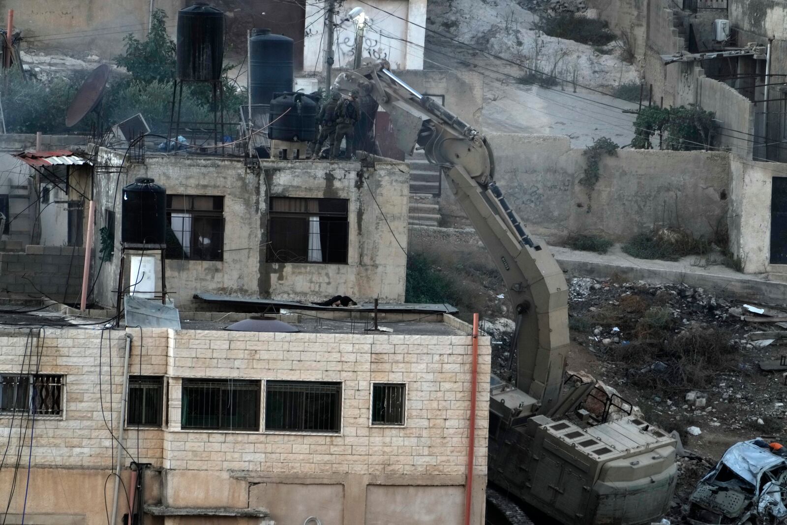 EDS NOTE: GRAPHIC CONTENT - Israeli soldiers look over a rooftop in the West Bank town of Qatabiya near two corpses. The Israeli army raided the northern West Bank town on Thursday, as violence surges across the Israeli-occupied territory. Thursday, Sept.19, 2024. (AP Photo/Majdi Mohammed)