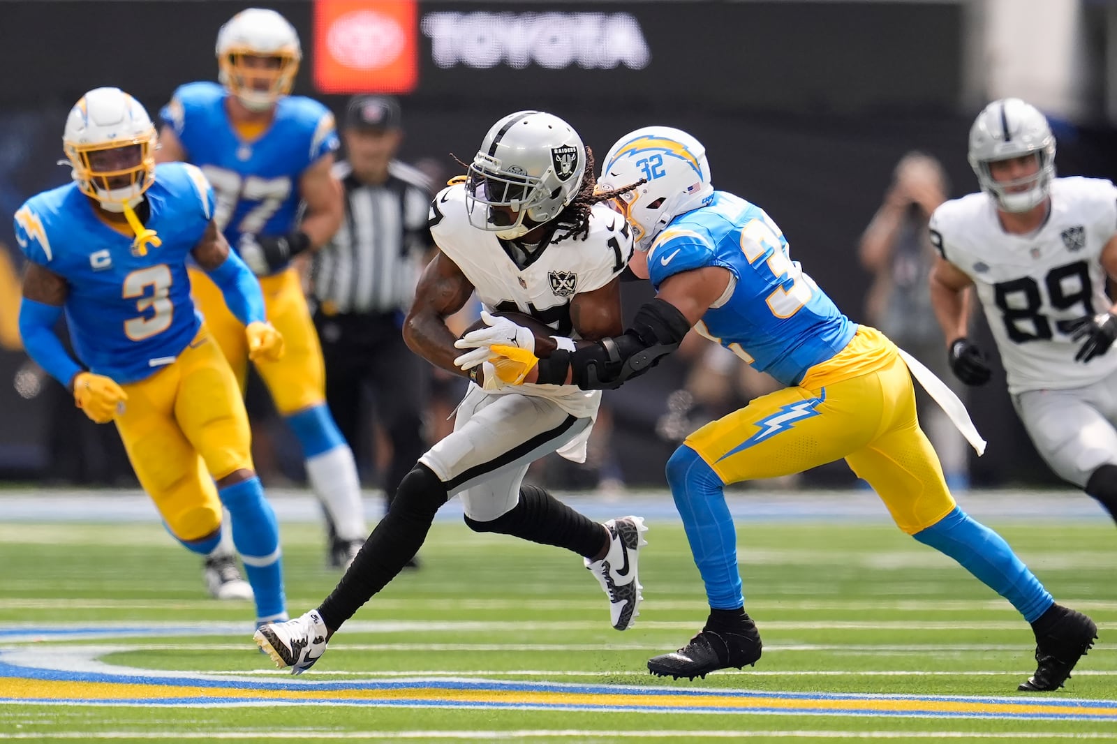 Las Vegas Raiders wide receiver Davante Adams, middle, runs against Los Angeles Chargers safety Alohi Gilman (32) during the first half of an NFL football game, Sunday, Sept. 8, 2024, in Inglewood, Calif. (AP Photo/Marcio Jose Sanchez)