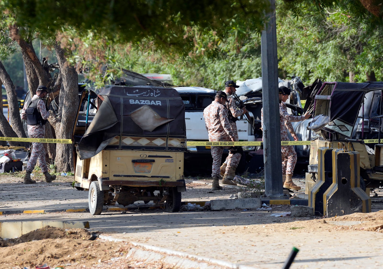 Security officials work on the site of an explosion that caused injures and destroyed vehicles outside the Karachi airport, Pakistan, Monday, Oct. 7, 2024. Pakistani Baloch separatists claim deadly bomb attack that killed 2 Chinese near Karachi airport. (AP Photo/Fareed Khan)