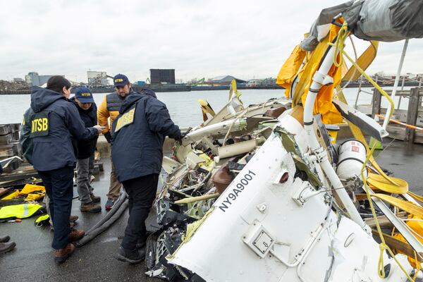 In this image released by the National Transportation Safety Board, an NTSB team surveys the wreckage, April 11, 2025, in Jersey City, N.J., recovered from the Bell 206L-4 helicopter that crashed into Hudson River on April 10, between New York City and New Jersey. (NTSB via AP)