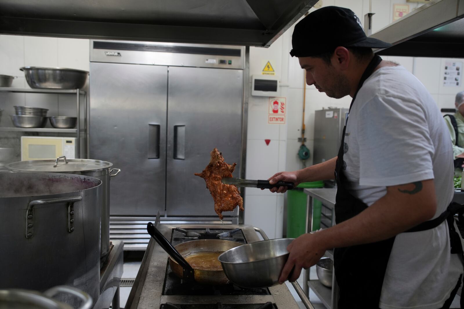 A cook fries guinea pigs at a restaurant in Lima, Peru, Thursday, Oct. 3, 2024. Guinea pigs, locally known as 'cuy,' have been traditionally raised for meat consumption since pre-Inca times. (AP Photo/Guadalupe Pardo)