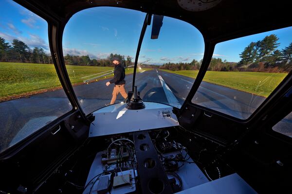 With communications and control components installed where a pilot would sit, Brett Worden, production manager at Rotor Technologies, carries a spray boom following a test flight of an unmanned semi-autonomous helicopter at Intervale Airport, Monday, Nov. 11, 2024, in Henniker, N.H. (AP Photo/Charles Krupa)