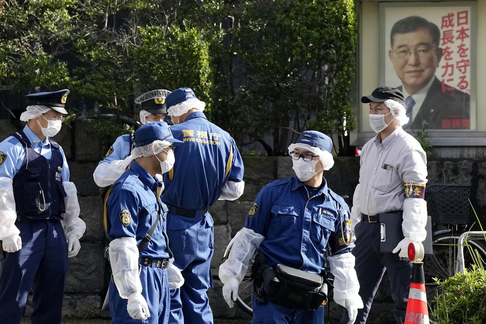 Police officers gather near the headquarters of Japan's ruling Liberal Democratic Party with a poster of Japan's Prime Minister and the party's head Shigeru Ishiba on display after a man threw firebombs into the headquarters in Tokyo Saturday, Oct. 19, 2024. (Kyodo News via AP)