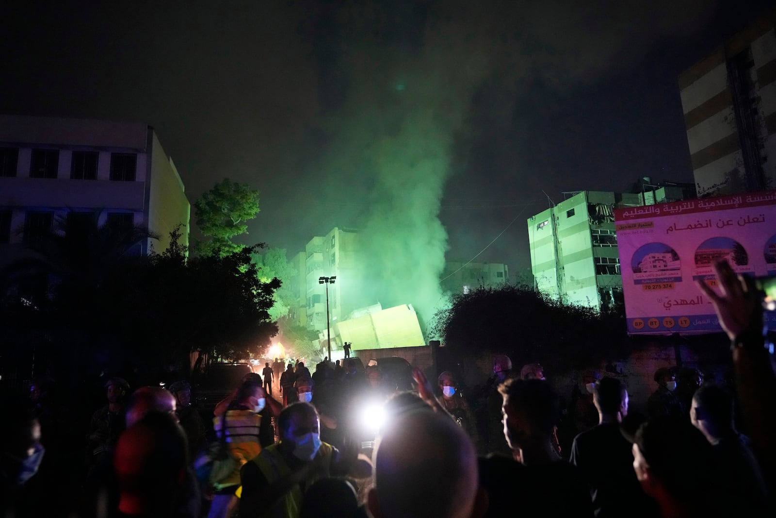 People gather as smoke rises from a collapsed building at the site of an Israeli airstrike in Beirut's southern suburbs, Friday, Sept. 27, 2024. (AP Photo/Hassan Ammar)