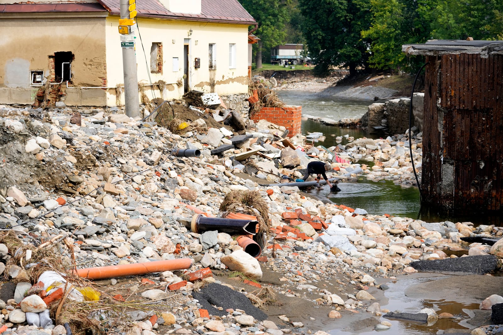 A woman gets a bucket of water as residents return to clean up after recent floods in Mikulovice, Czech Republic, Thursday, Sept. 19, 2024. (AP Photo/Petr David Josek)