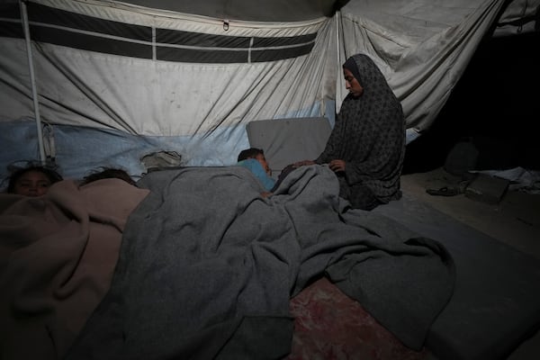 Shireen Daifallah, who was displaced from northern Gaza, checks one of her children in their tent at a camp for displaced people in Deir al-Balah. Gaza Strip, Saturday, Nov. 30, 2024. (AP Photo/Abdel Kareem Hana)