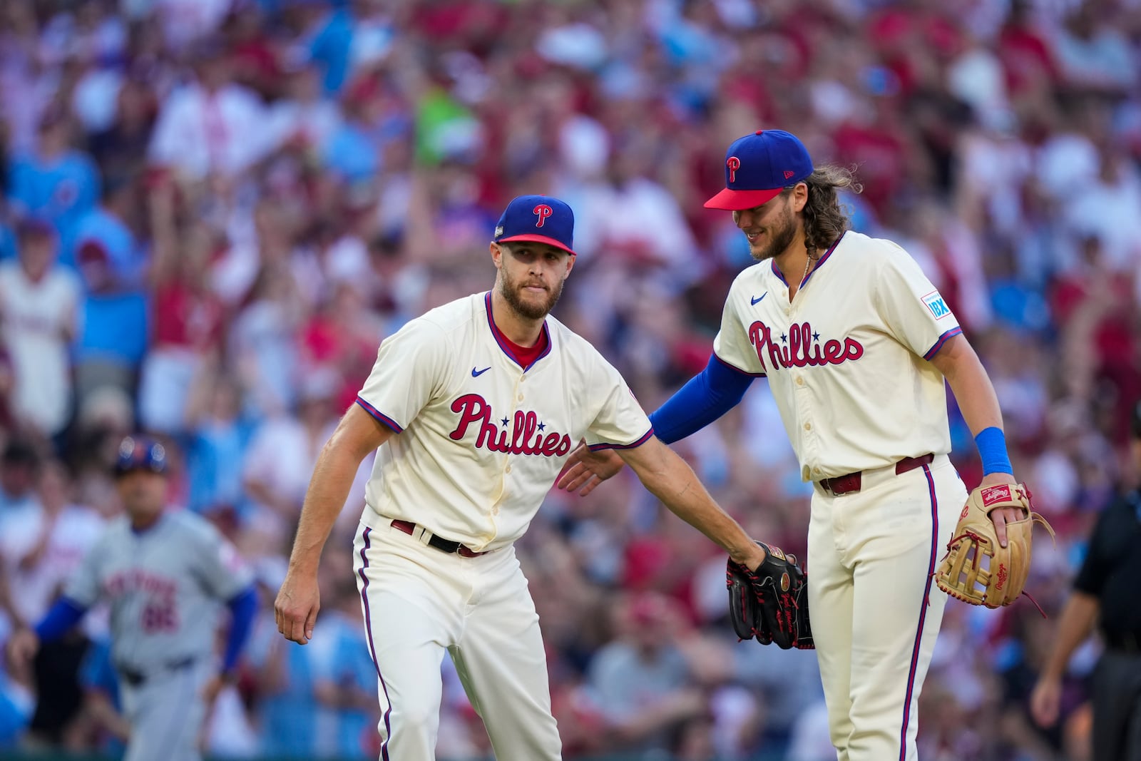 Philadelphia Phillies' Zack Wheeler, center, and Alec Bohm, react after Wheeler caught a fly out hit by New York Mets' Francisco Lindor during the third inning of Game 1 of a baseball NL Division Series, Saturday, Oct. 5, 2024, in Philadelphia. (AP Photo/Matt Slocum)