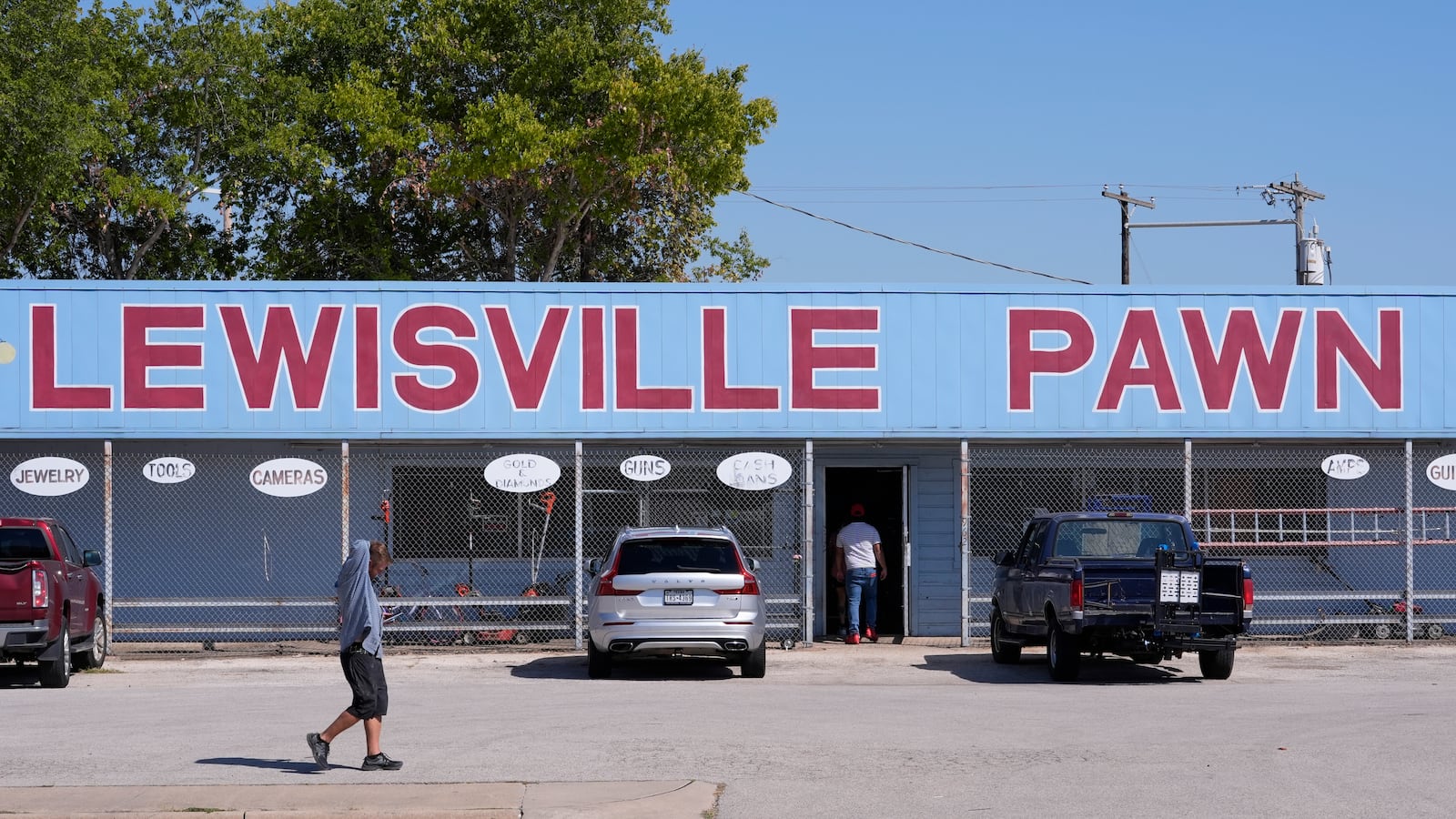 People walk and enter a business in Lewisville, Texas, Friday, Oct. 4, 2024. (AP Photo/LM Otero)