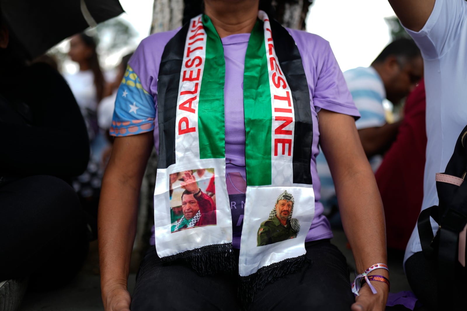 Rosa Teran wears a scarf with the image of Venezuelan late president Hugo Chavez, left, and late Palestinian leader Yasser Arafat, right, during a march to the United Nations office to show support for the Palestinian people in Caracas, Venezuela, Saturday, Oct. 5, 2024, days before the one-year anniversary of Hamas' attack in southern Israel and Israel's response to go to war on Hamas. (AP Photo/Ariana Cubillos)