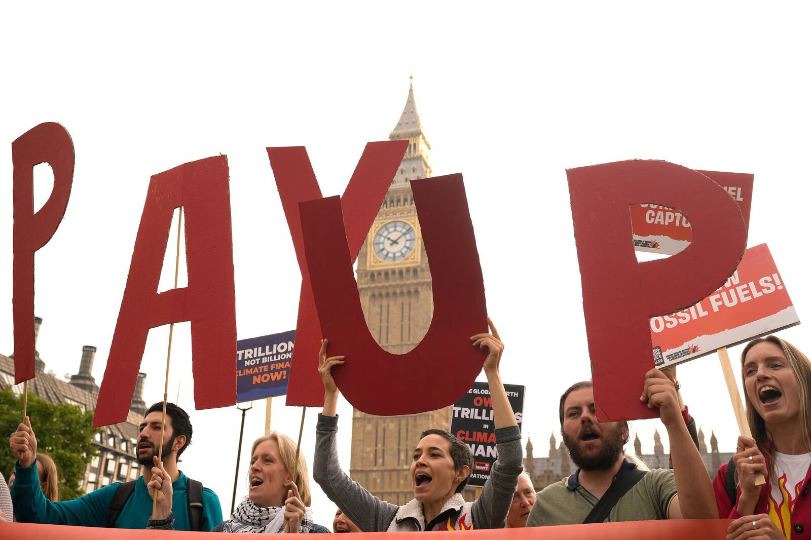 Protesters hold letters and shout during a global week of action for climate finance and a fossil free future protest in London, Friday, Sept. 20, 2024.(AP Photo/Frank Augstein)