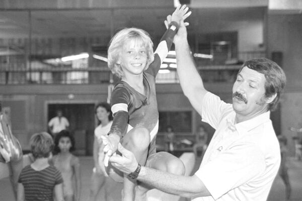 FILE - Olympic gymnastics coach Bela Karolyi, right, instructs Sara Tank on the balance beam at his Olympic training facility in north Houston, Aug. 12, 1985. (AP Photo/Richard J. Carson, File)