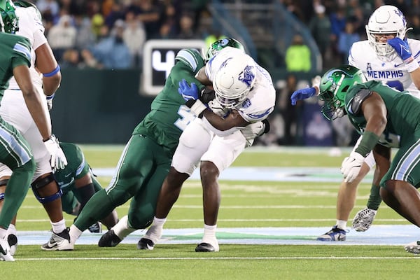 Tulane linebacker Chris Rodgers (4) tackles Memphis wide receiver Roc Taylor, center right, during the first half of an NCAA college football game in New Orleans, Thursday, Nov. 28, 2024. (AP Photo/Peter Forest)