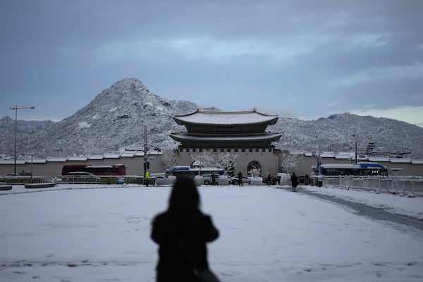 A pedestrian stops to take photo the snow-covered Gwanghwamun, the main gate of the 14th-century Gyeongbok Palace, one of South Korea's well known landmarks, in Seoul, South Korea, Wednesday, Nov. 27, 2024. (AP Photo/Lee Jin-man)