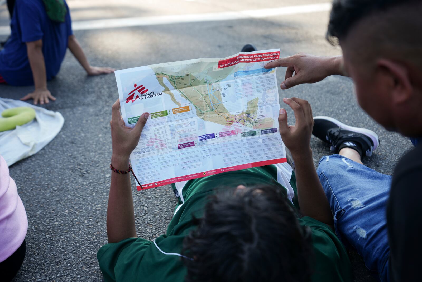 Migrants, who are part of a a caravan heading toward the country's northern border and ultimately the United States, check a map during a break, on the outskirts of Escuintla, southern Mexico, Thursday, Nov. 7, 2024. (AP Photo/Moises Castillo)