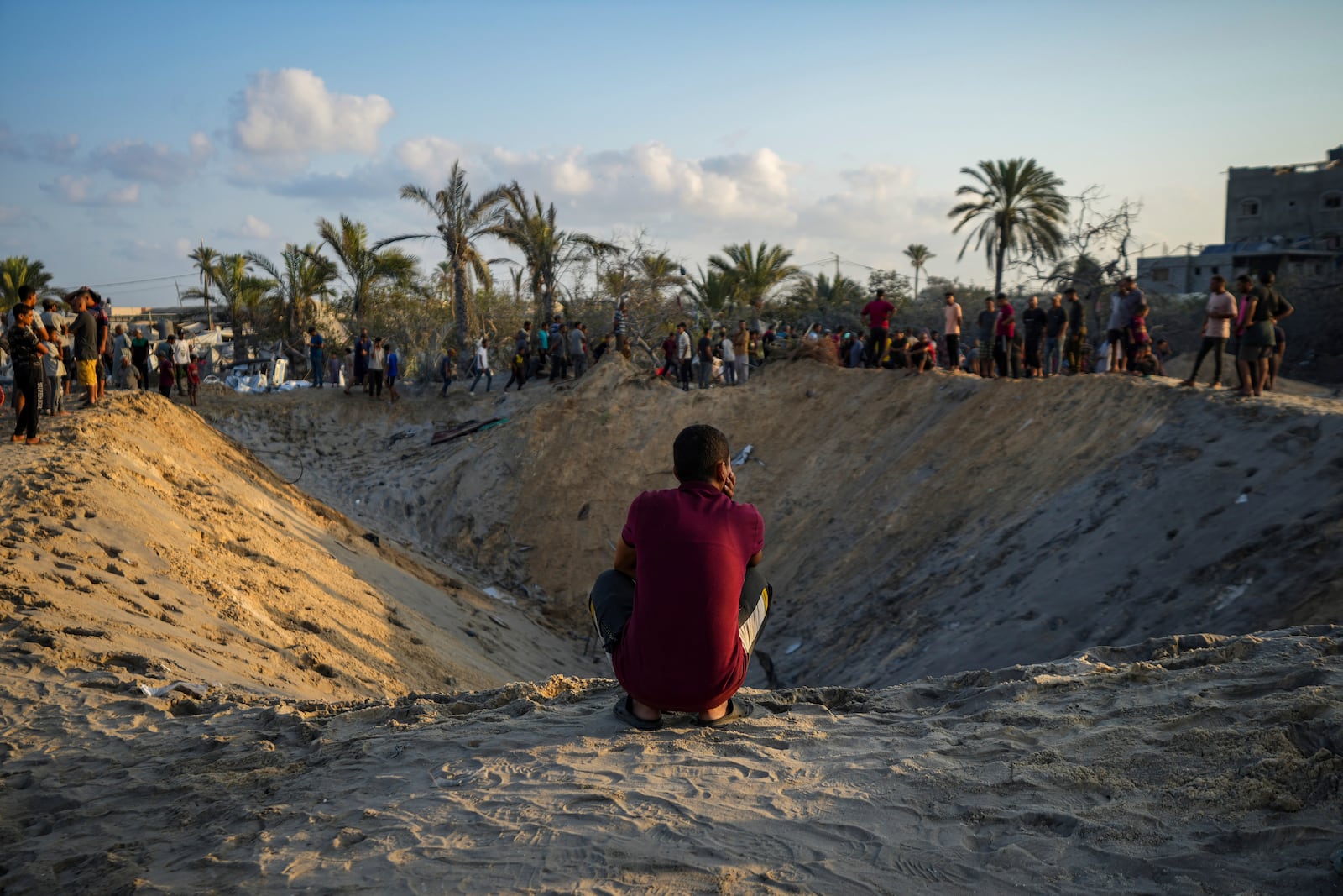 FILE - Palestinians look at the destruction after an Israeli airstrike on a crowded tent camp housing people displaced by the war in Muwasi, Gaza Strip, on Sept. 10, 2024. (AP Photo/Abdel Kareem Hana, File)