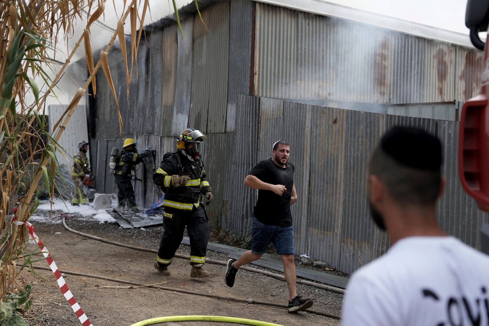 Residents run away as emergency personnel respond after a rocket apparently fired from Gaza hits Kfar Chabad Tel Aviv, Monday, Oct. 7, 2024. (AP Photo/Oded Balilty)