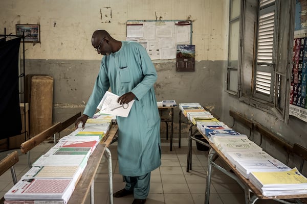 A man collects voting cards, that are set on a table, before casting his vote for legislative elections at a polling station in Dakar, Senegal Sunday, Nov. 17, 2024. (AP Photo/Annika Hammerschlag)