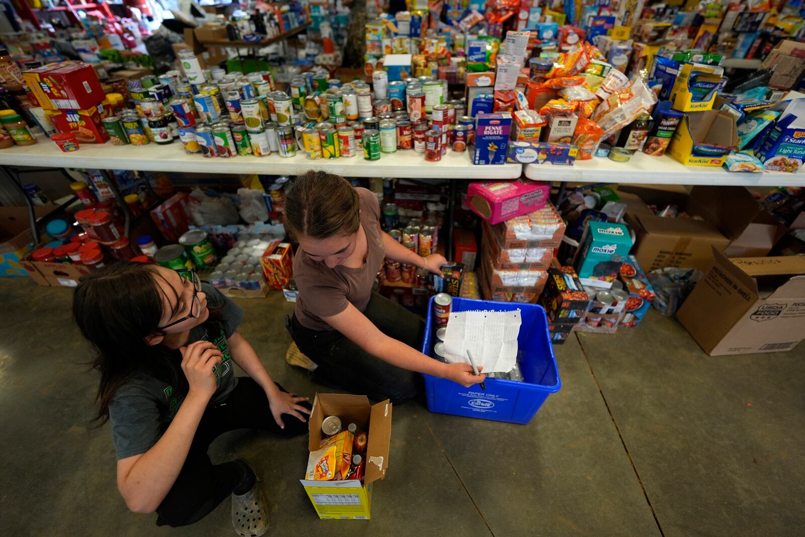 Volunteers gather food for families at the volunteer fire station in the aftermath of Hurricane Helene, Thursday, Oct. 3, 2024, in Pensacola, N.C. (AP Photo/Mike Stewart)