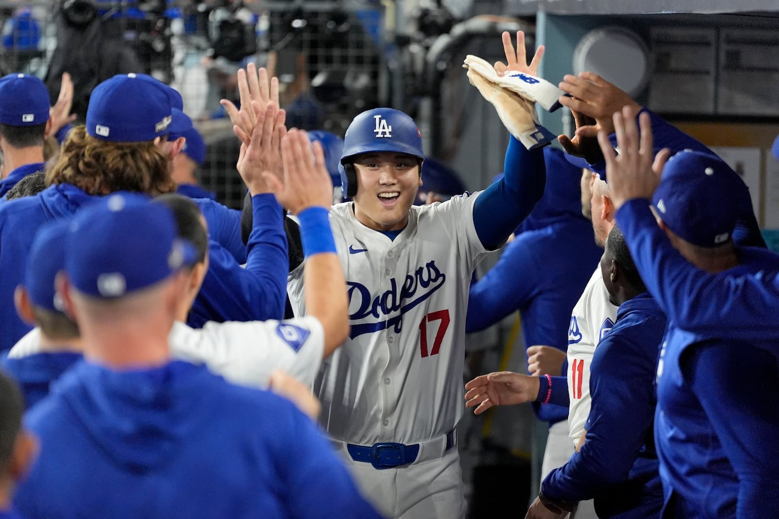 Los Angeles Dodgers' Shohei Ohtani (17) celebrates in the dugout after scoring on a single by Teoscar Hernández during the fourth inning in Game 1 of baseball's NL Division Series against the San Diego Padres, Saturday, Oct. 5, 2024, in Los Angeles. (AP Photo/Ashley Landis)