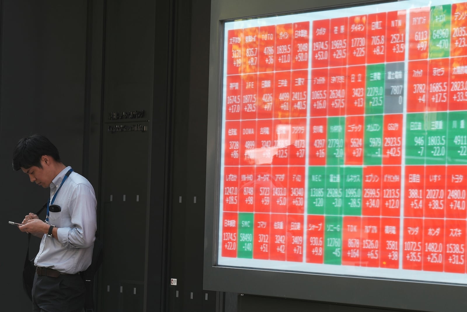 FILE - A person stands near an electronic stock board showing Japan's Nikkei index at a securities firm Wednesday, Sept. 18, 2024, in Tokyo. (AP Photo/Eugene Hoshiko, File)