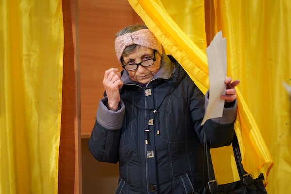 A woman exits a voting cabin before casting her vote in the country's parliamentary election in Mogosoaia, Romania, Sunday, Dec. 1, 2024. (AP Photo/Vadim Ghirda)